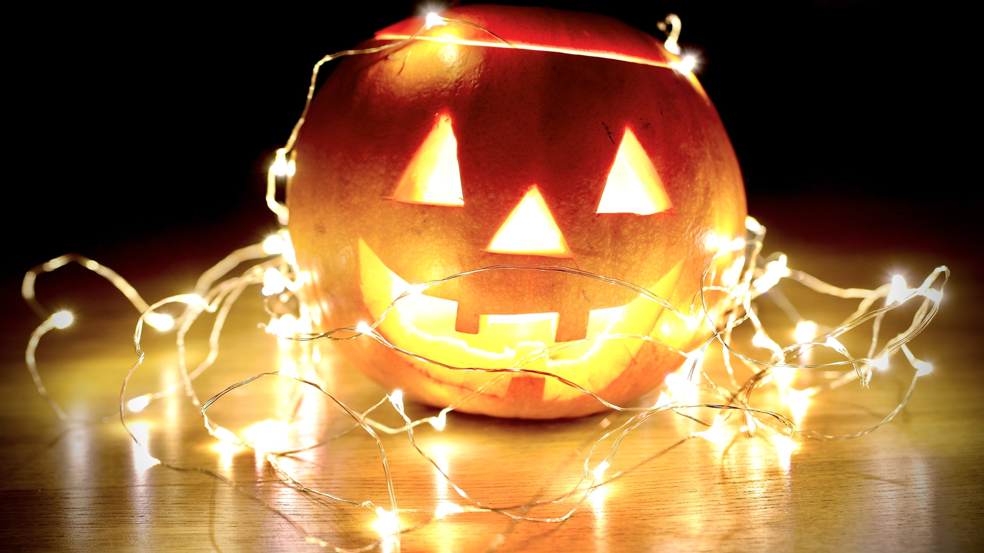 Von innen erleuchteter Halloween-Kürbis mit Fratze und Lichterkette